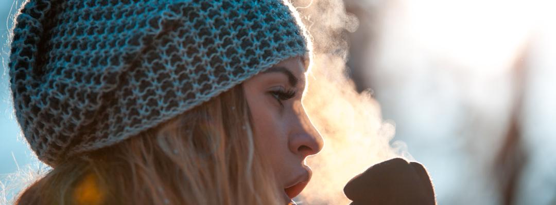 Woman breathing on her hands to keep them warm at cold winter day