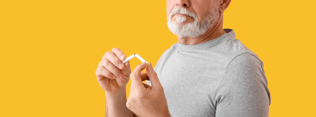 Reifender Mann mit aufgebrachtem Nikotinpflaster und gebrochener Zigarette auf Farbhintergrund. Raucherentwöhnung