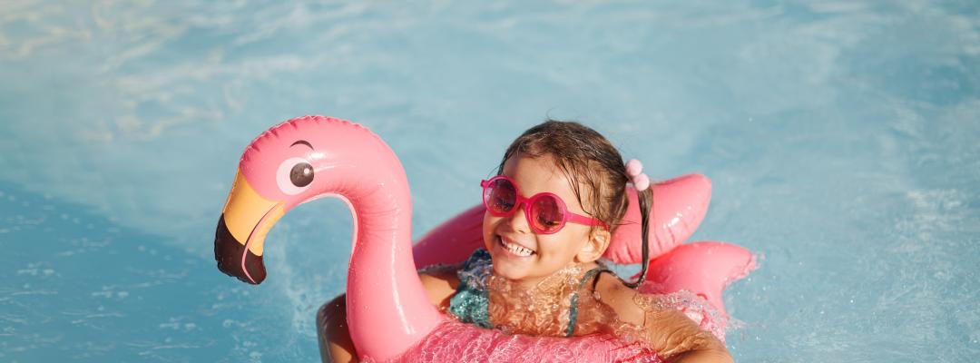 Cute funny toddler girl in a sunglasses relaxing on inflatable toy ring floating in pool have fun during summer vacation. Child having fun in swimming pool.