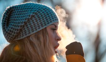 Woman breathing on her hands to keep them warm at cold winter day
