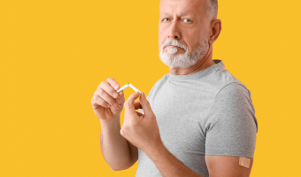 Reifender Mann mit aufgebrachtem Nikotinpflaster und gebrochener Zigarette auf Farbhintergrund. Raucherentwöhnung