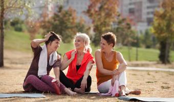 Aktive ältere Frauen im Fitnesstraining im öffentlichen Park, entspannen und sprechen nach dem Training. Fröhlich reife Freundinnen im Freien