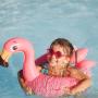 Cute funny toddler girl in a sunglasses relaxing on inflatable toy ring floating in pool have fun during summer vacation. Child having fun in swimming pool.